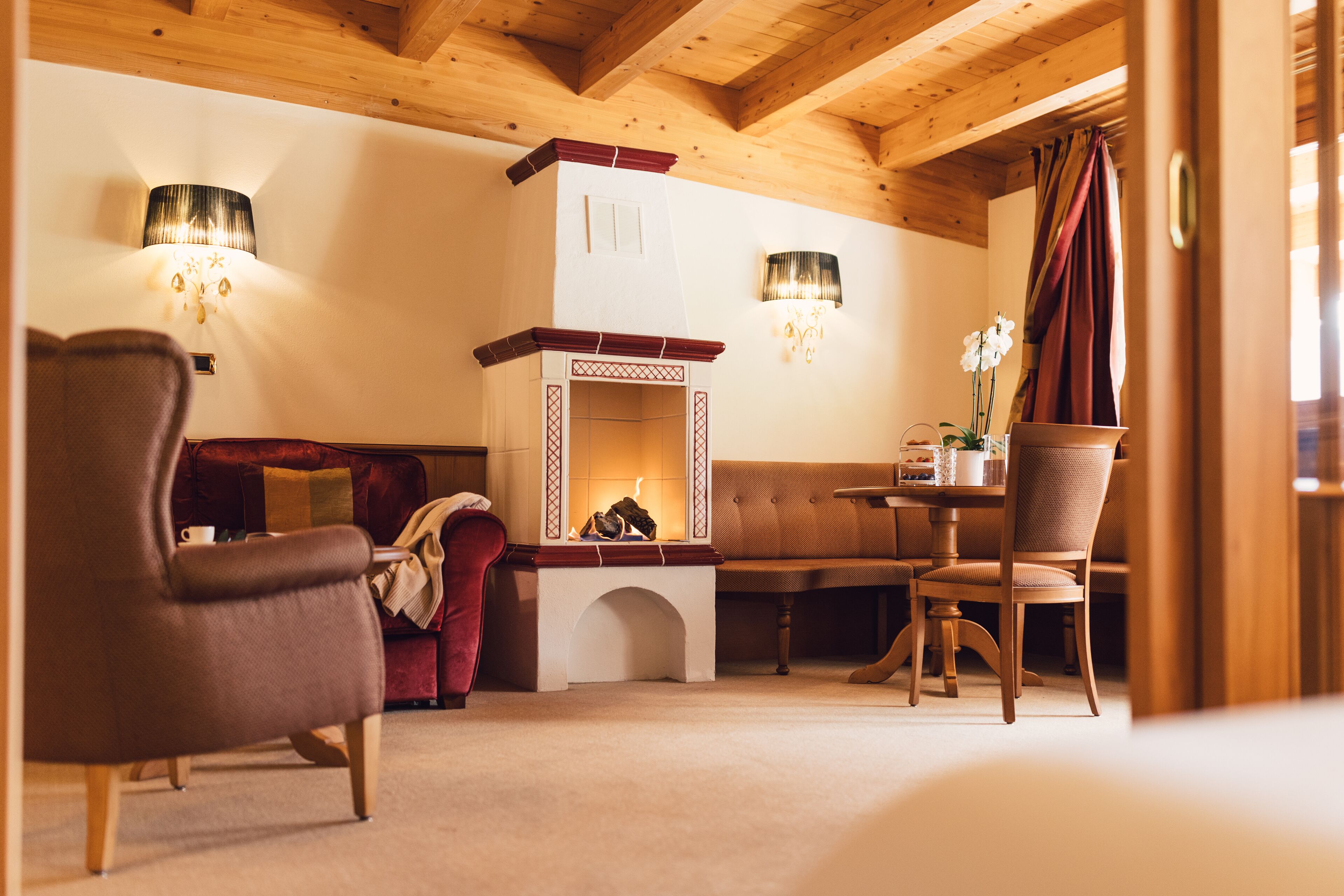 A cozy room with a fireplace, a sofa, a dining table with chairs, and two lamps.