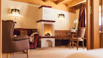 A cozy room with a fireplace, a sofa, a dining table with chairs, and two lamps.