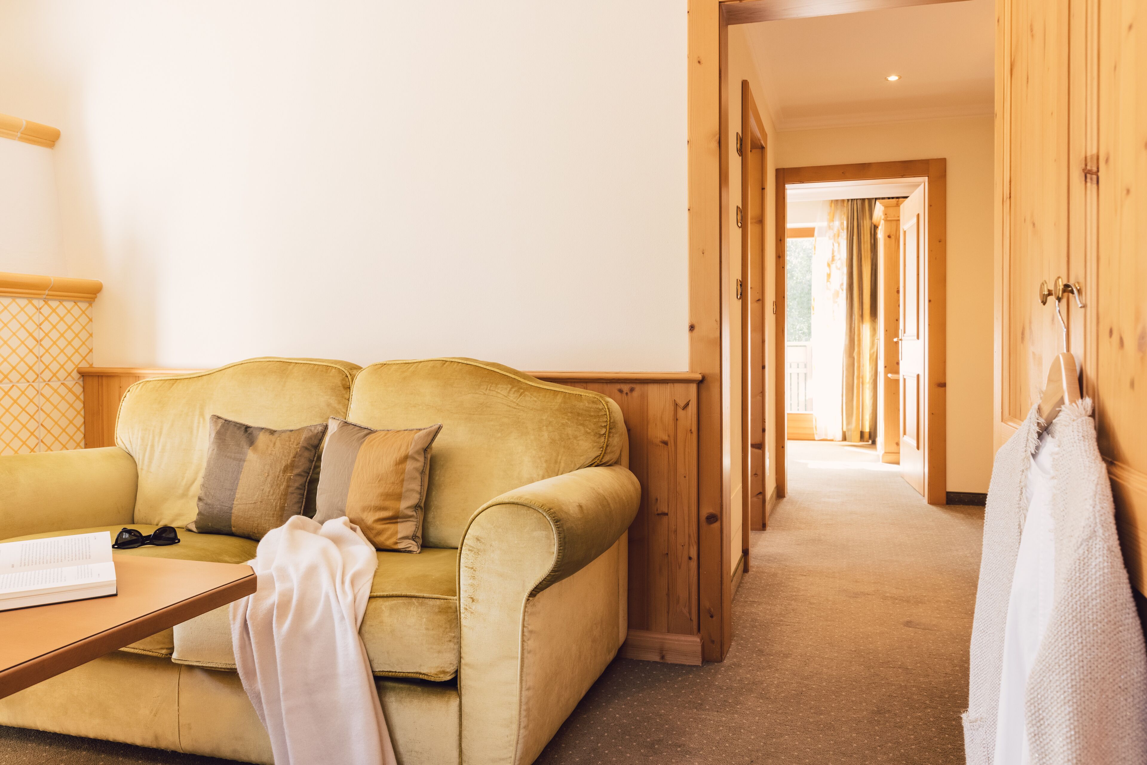 A cozy room with a yellow sofa, a wooden door, and a hallway leading to another area.