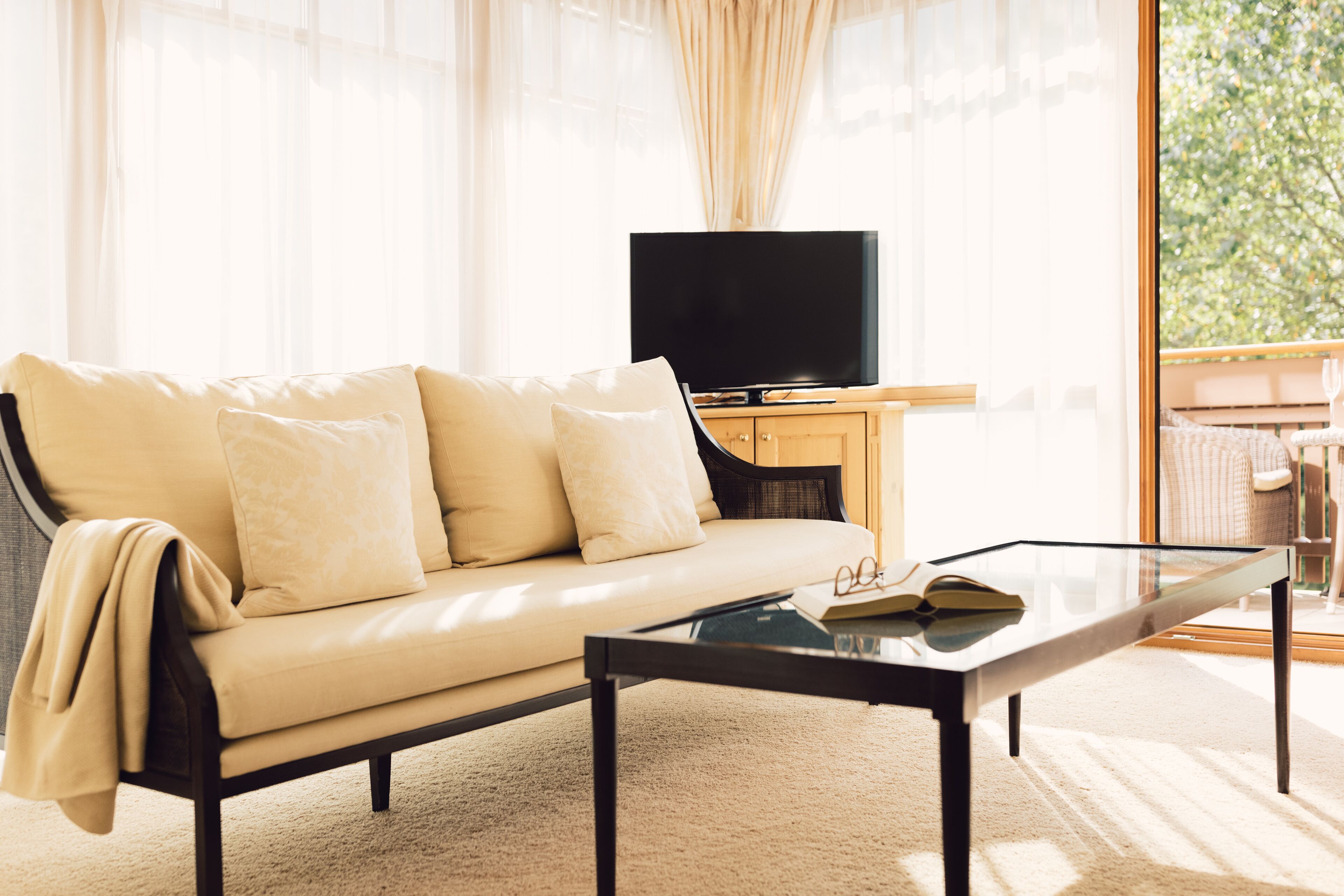 A living room with a sofa, a glass coffee table, and a television on a wooden cabinet.