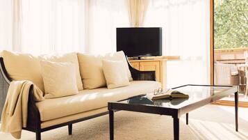 A living room with a sofa, a glass coffee table, and a television on a wooden cabinet.