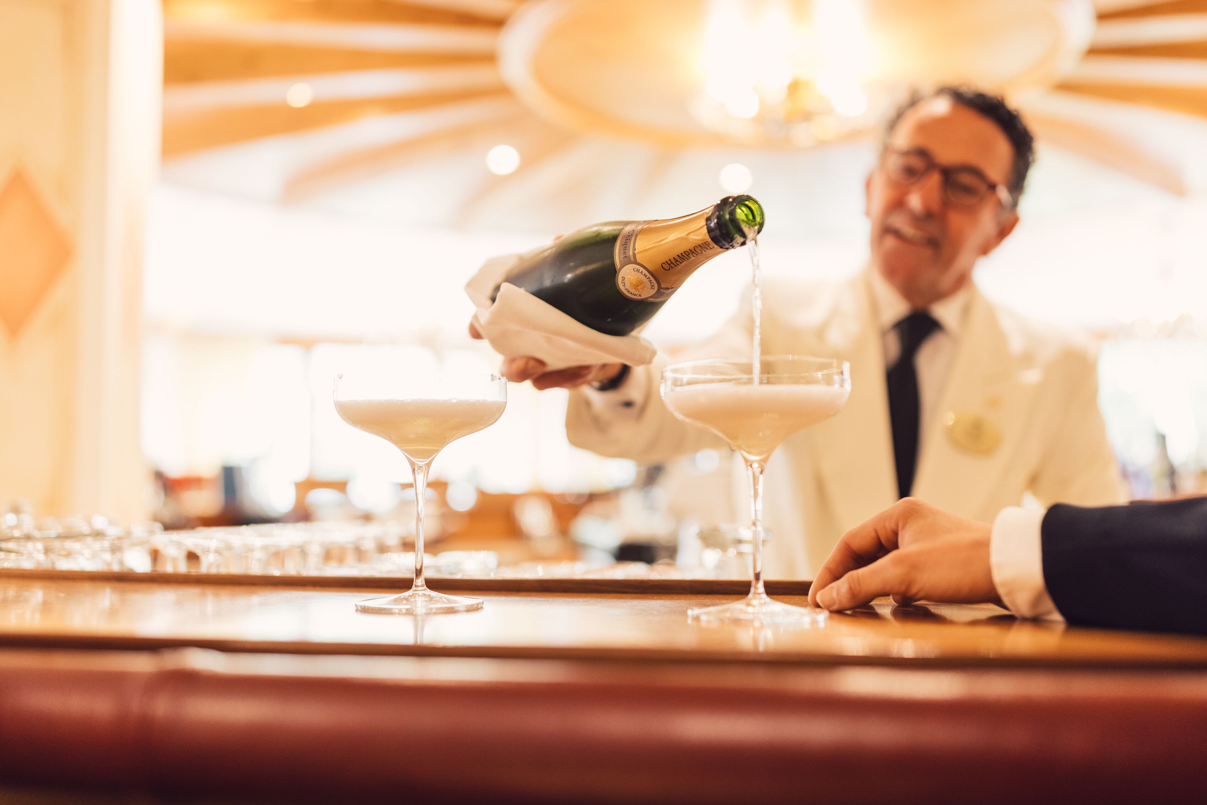 A person pouring a drink into a glass at a bar.