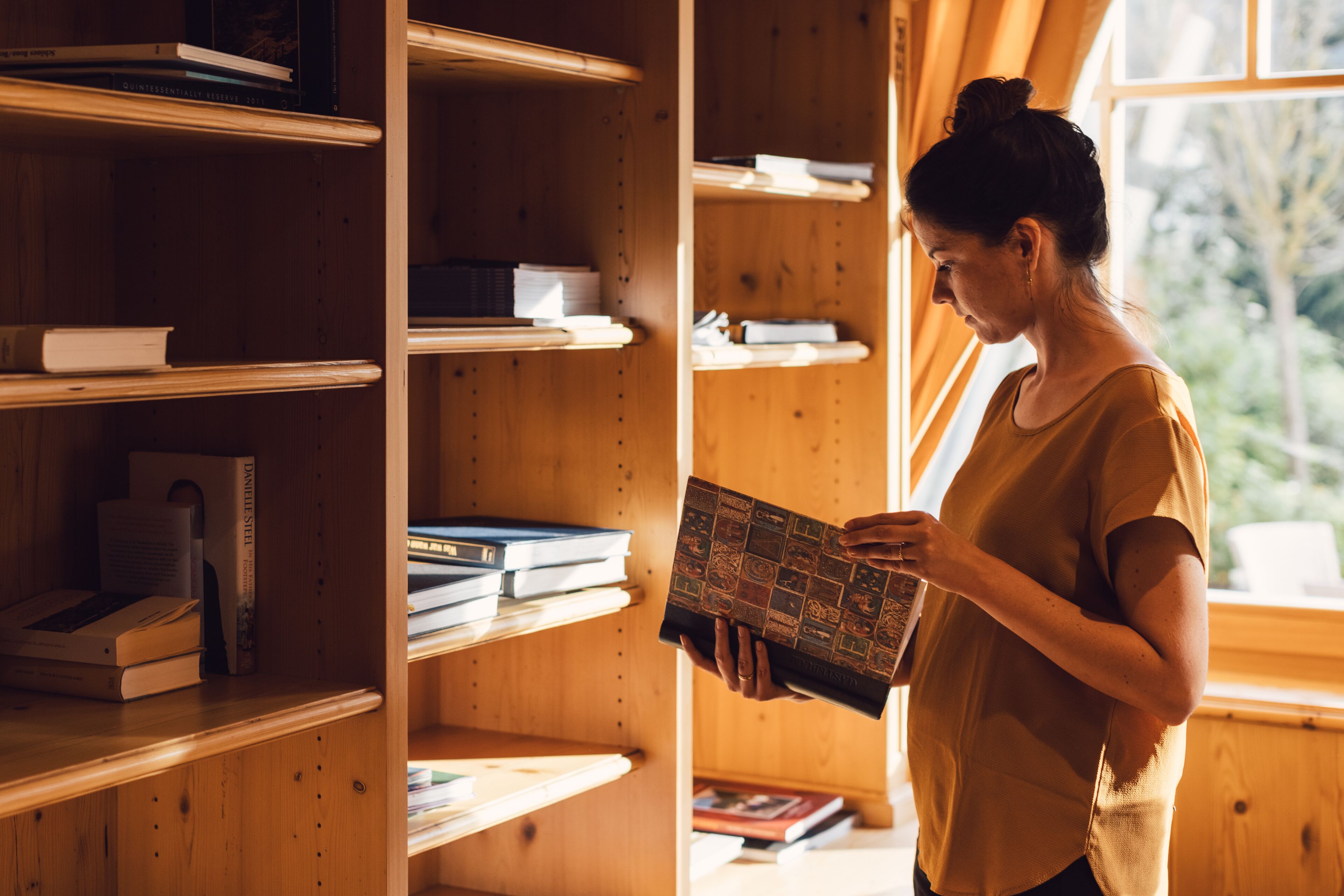 Eine Person liest ein Buch in einem Raum mit Bücherregalen voller Bücher.