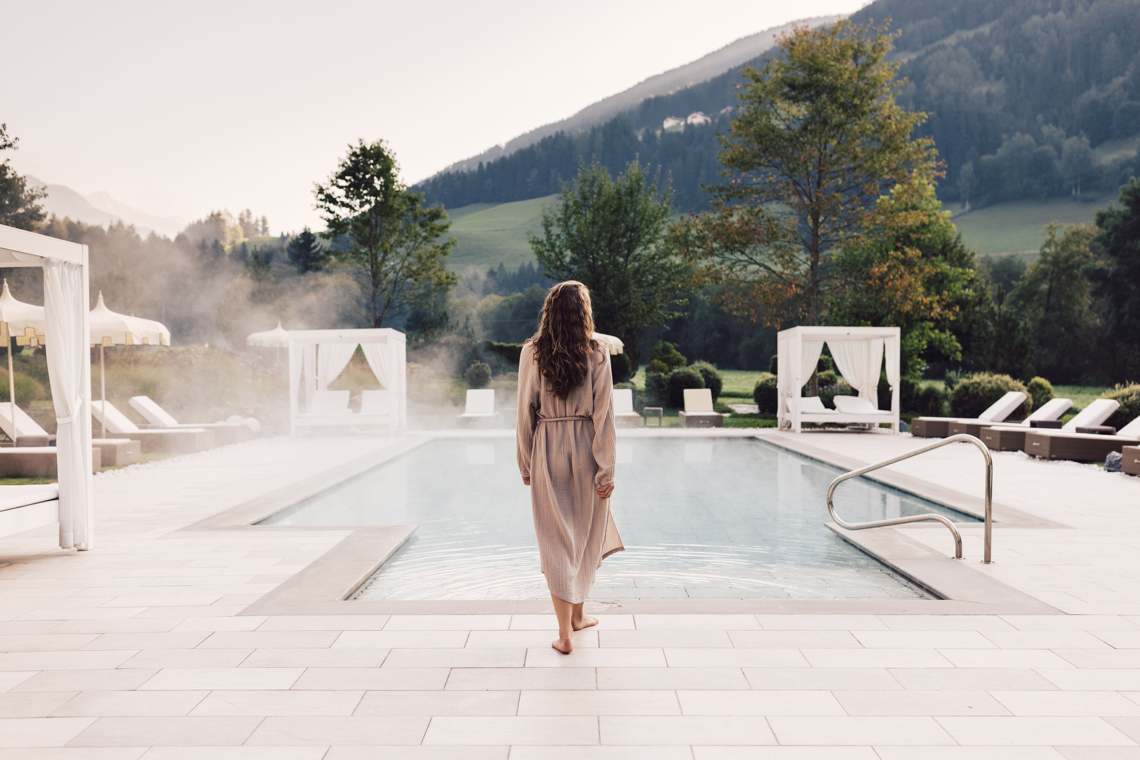 Un espace piscine doté de chaises longues et offrant une vue sur un paysage montagneux.