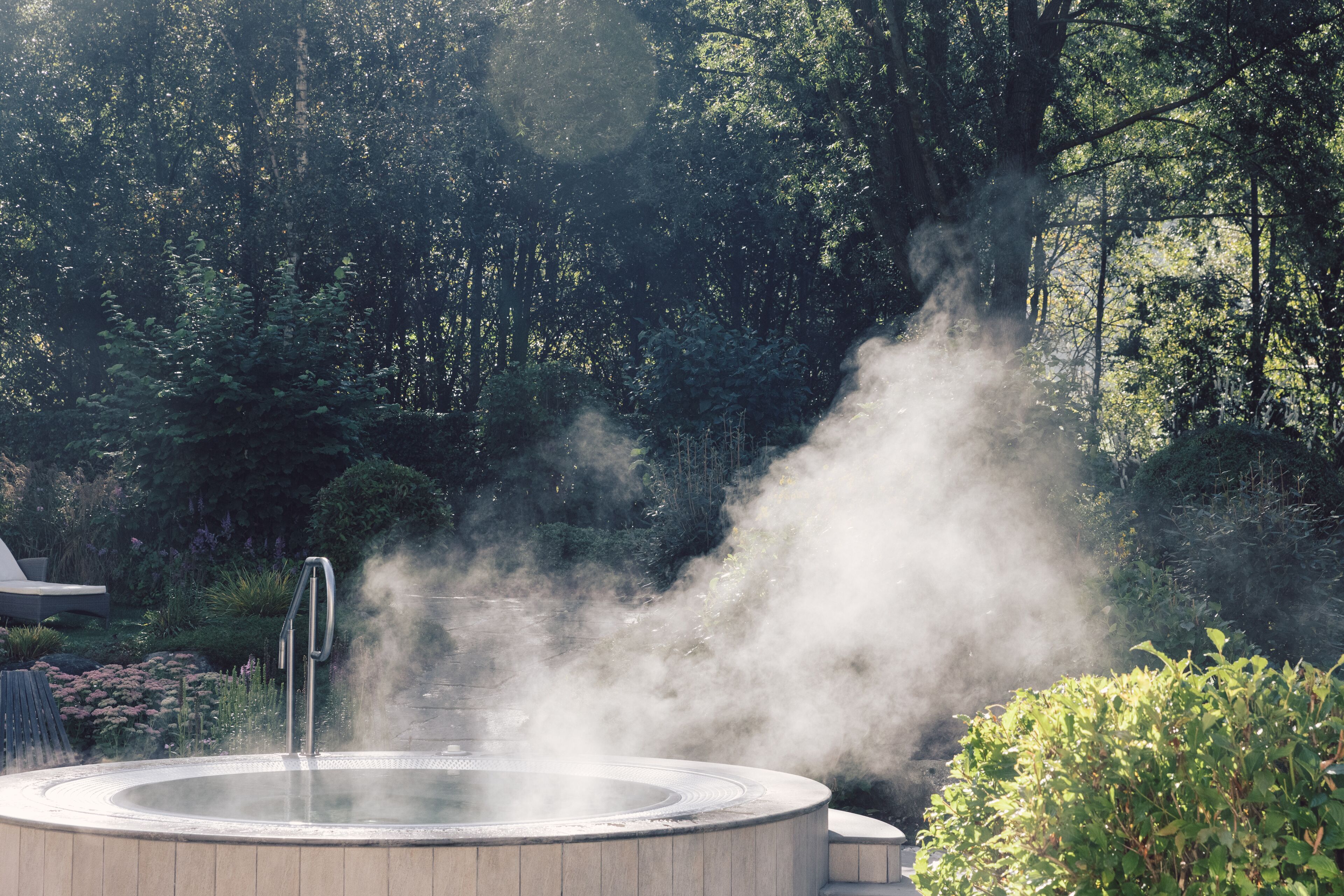 A hot tub surrounded by lush greenery and trees.