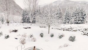 A snow-covered landscape with a hot tub in the foreground and trees in the background. - Alpenpalace Luxury Hideaway & Spa Retreat (Valle Aurina)