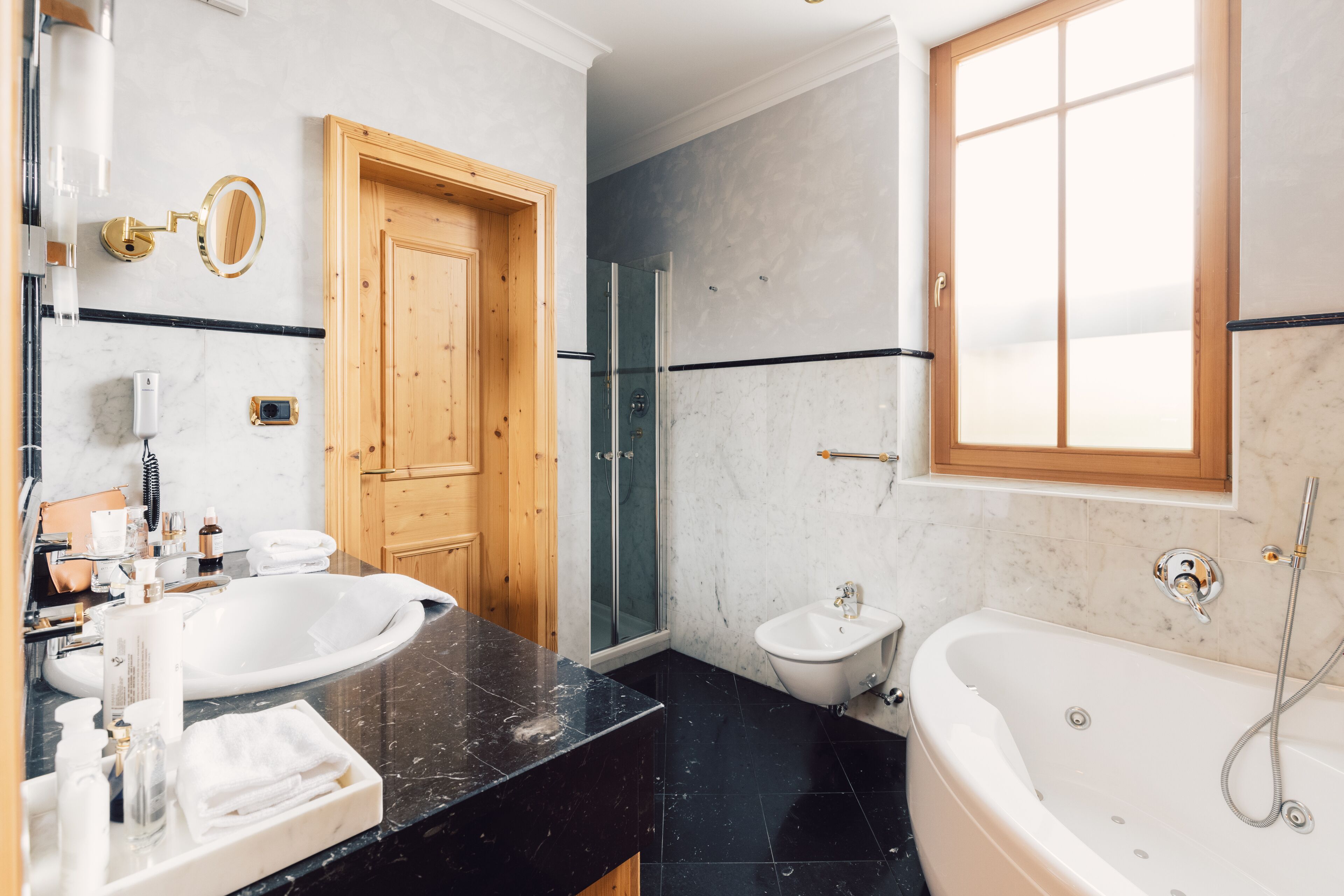 Une salle de bain moderne dotée d’une grande baignoire, d’une douche séparée, d’un meuble-lavabo et d’une porte en bois.