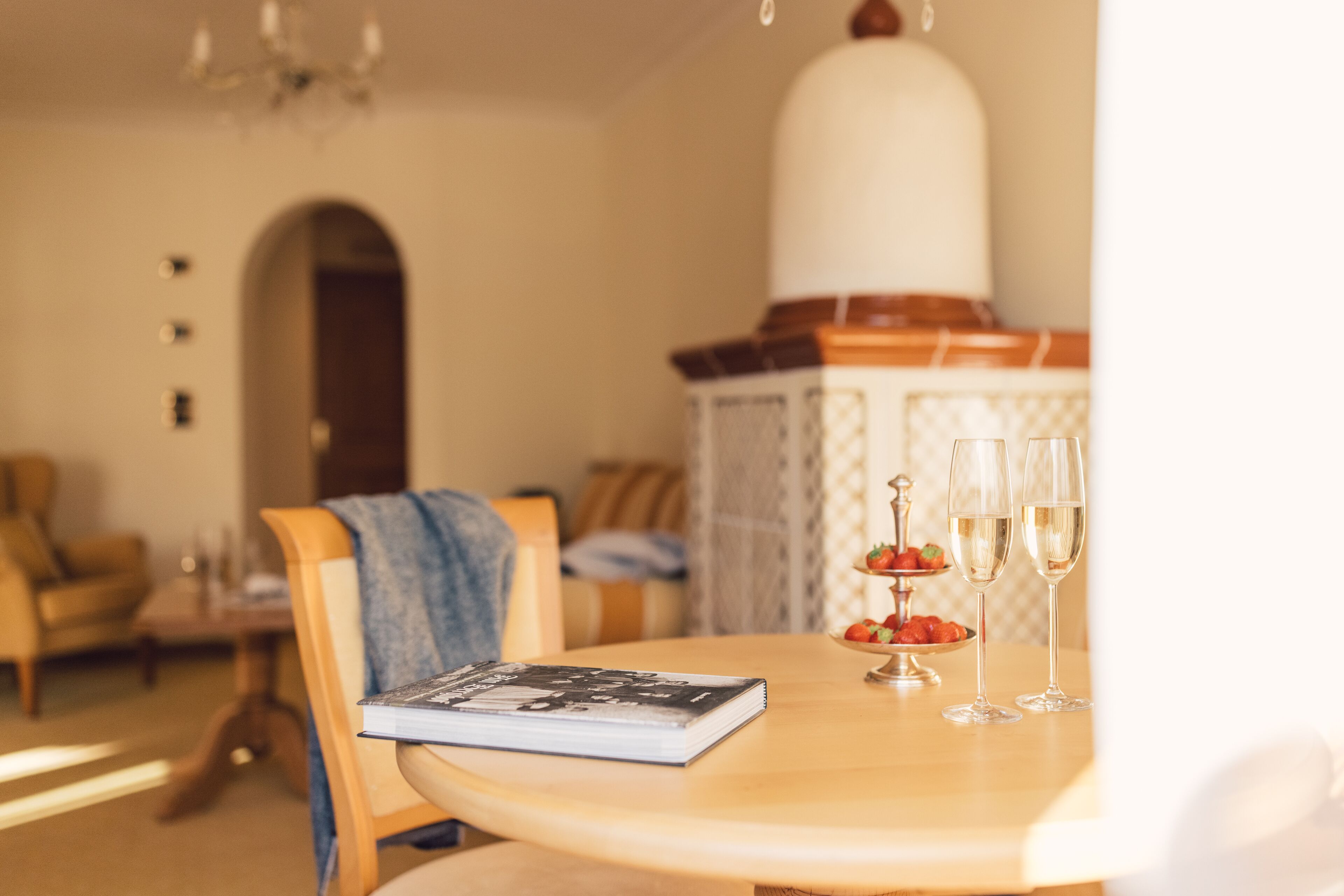 Una mesa de comedor con un libro, dos copas de champán y un cuenco de fruta.