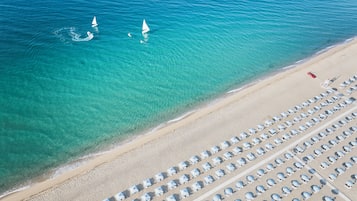 En privat strand, liggestole, parasoller, windsurfing