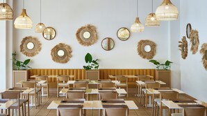 A dining area with tables and chairs, wooden ceiling beams, and wall-mounted decorative mirrors. - Serenè Resort (Cutro)