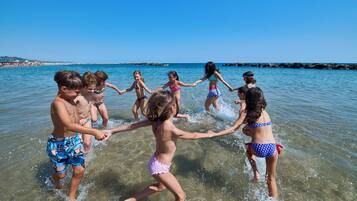 Un gruppo di bambini gioca in acque basse su una spiaggia.
