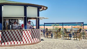 A beachside kiosk with a checkered floor, outdoor seating, and a view of the sea. - Serena Majestic Hotel (Montesilvano)