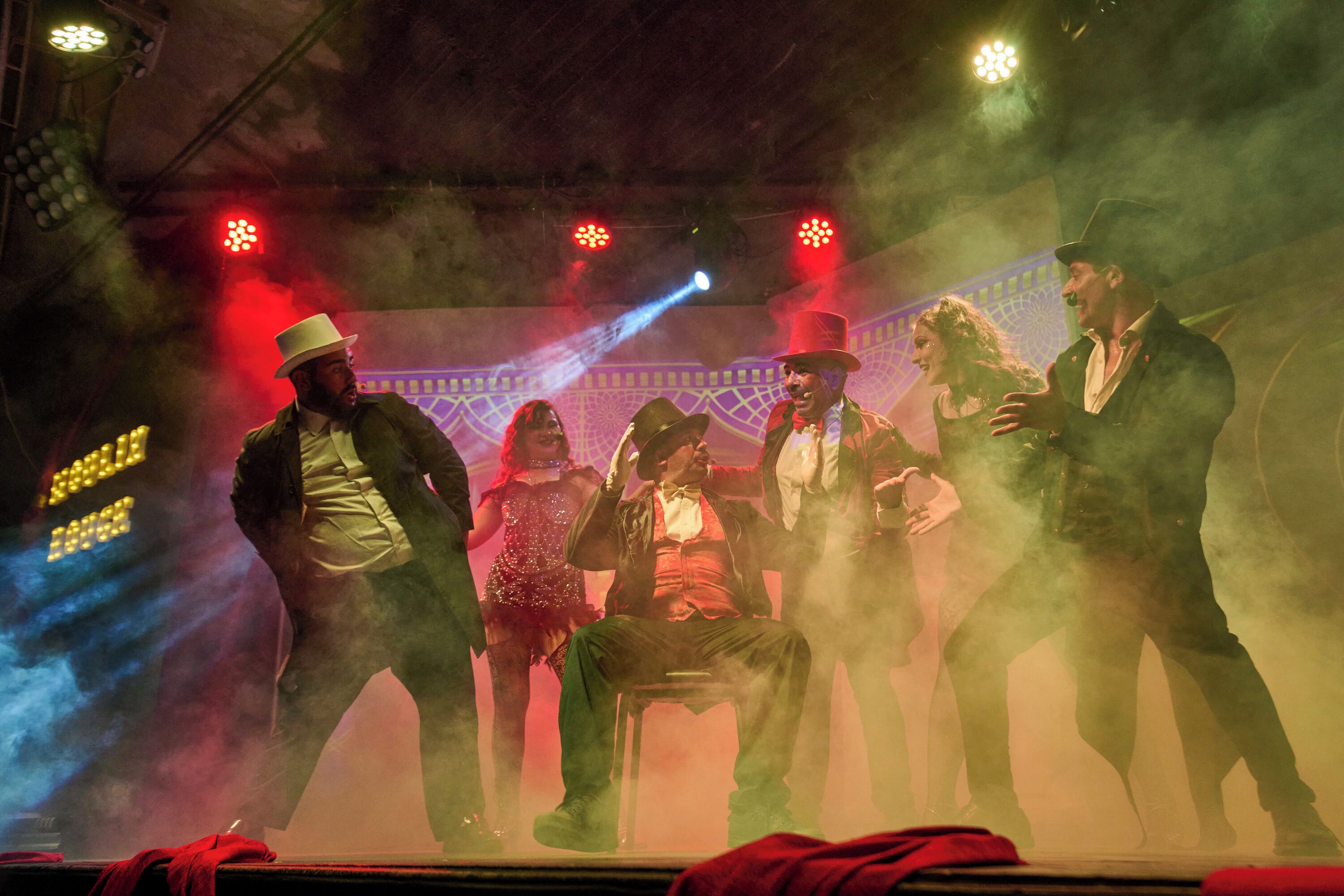 Un escenario con artistas, un efecto de humo e iluminación escénica.