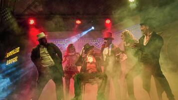 Un escenario con artistas, un efecto de humo e iluminación escénica.
