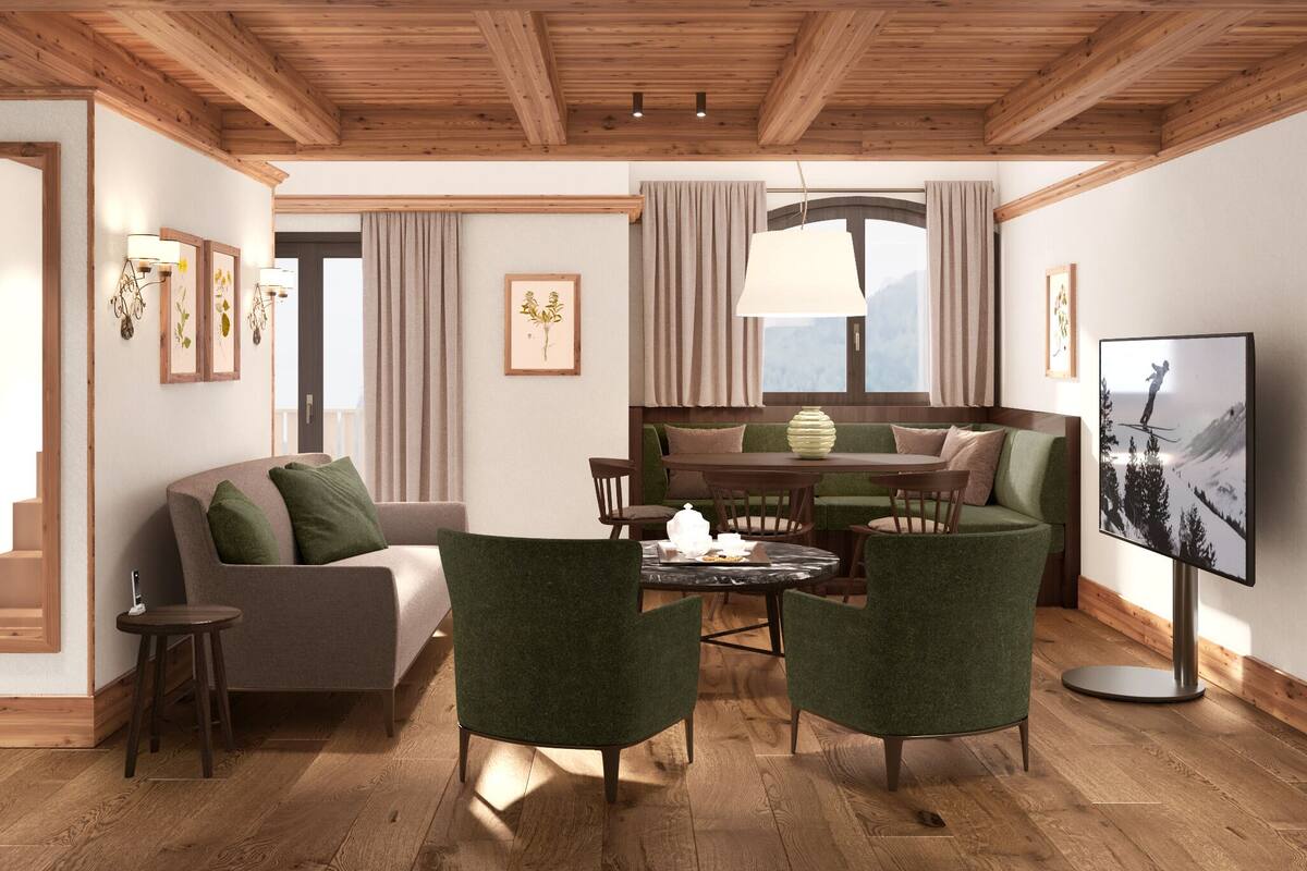 A cozy living room with a sofa, green armchairs, a coffee table, and a TV. There is a staircase leading to another room, and a window with curtains.