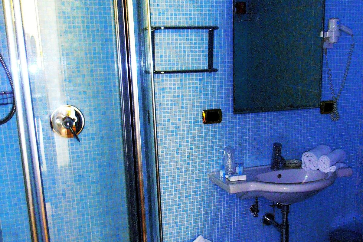 Une salle de bain avec une douche à parois de verre, un lavabo, un petit tabouret et un miroir.