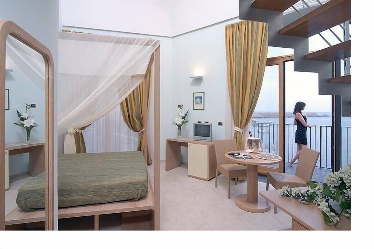 Une chambre d’hôtel moderne équipée d’un lit, d’un bureau, d’une chaise et d’un balcon avec vue.