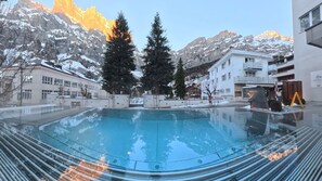 A swimming pool with a mountain backdrop, surrounded by buildings and trees.