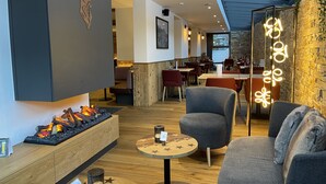 A modern interior with a fireplace, seating area, and a stone wall.
