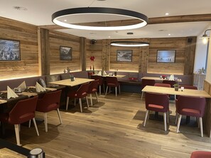 Un restaurant aux murs en bois, aux chaises rouges et aux bancs à carreaux.