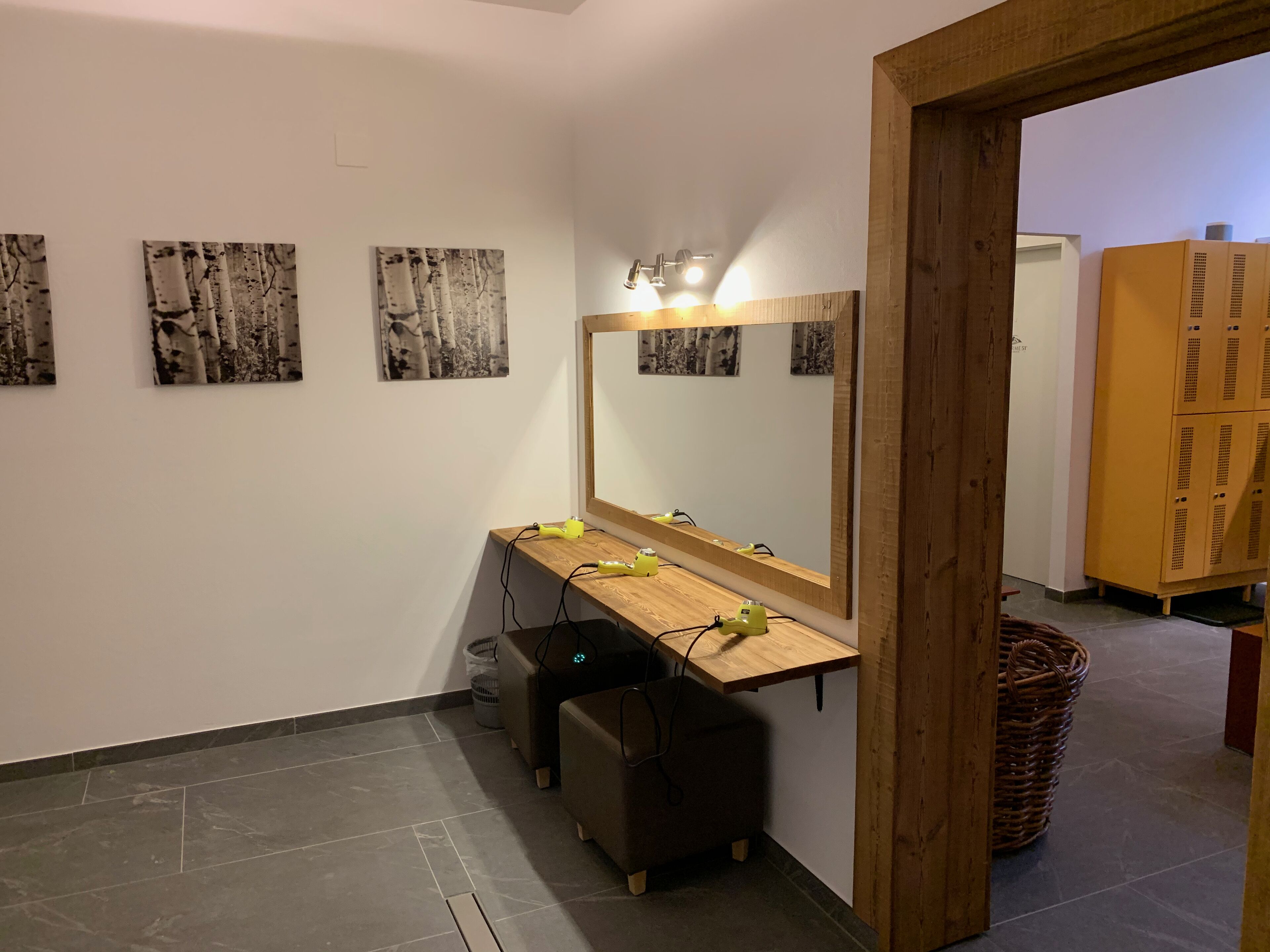 A bathroom with a wooden vanity, a large mirror, and three birch wood wall art pieces.