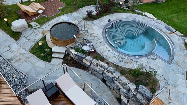 Un bain à remous et une piscine, avec des allées en pierre et des espaces de détente en plein air.