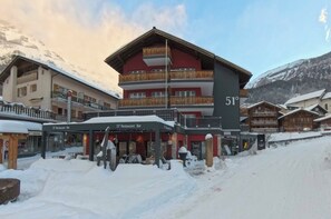 Un immeuble à plusieurs étages doté de balcons, d’un restaurant-bar et d’une enseigne indiquant « Restaurant-bar 51° ».