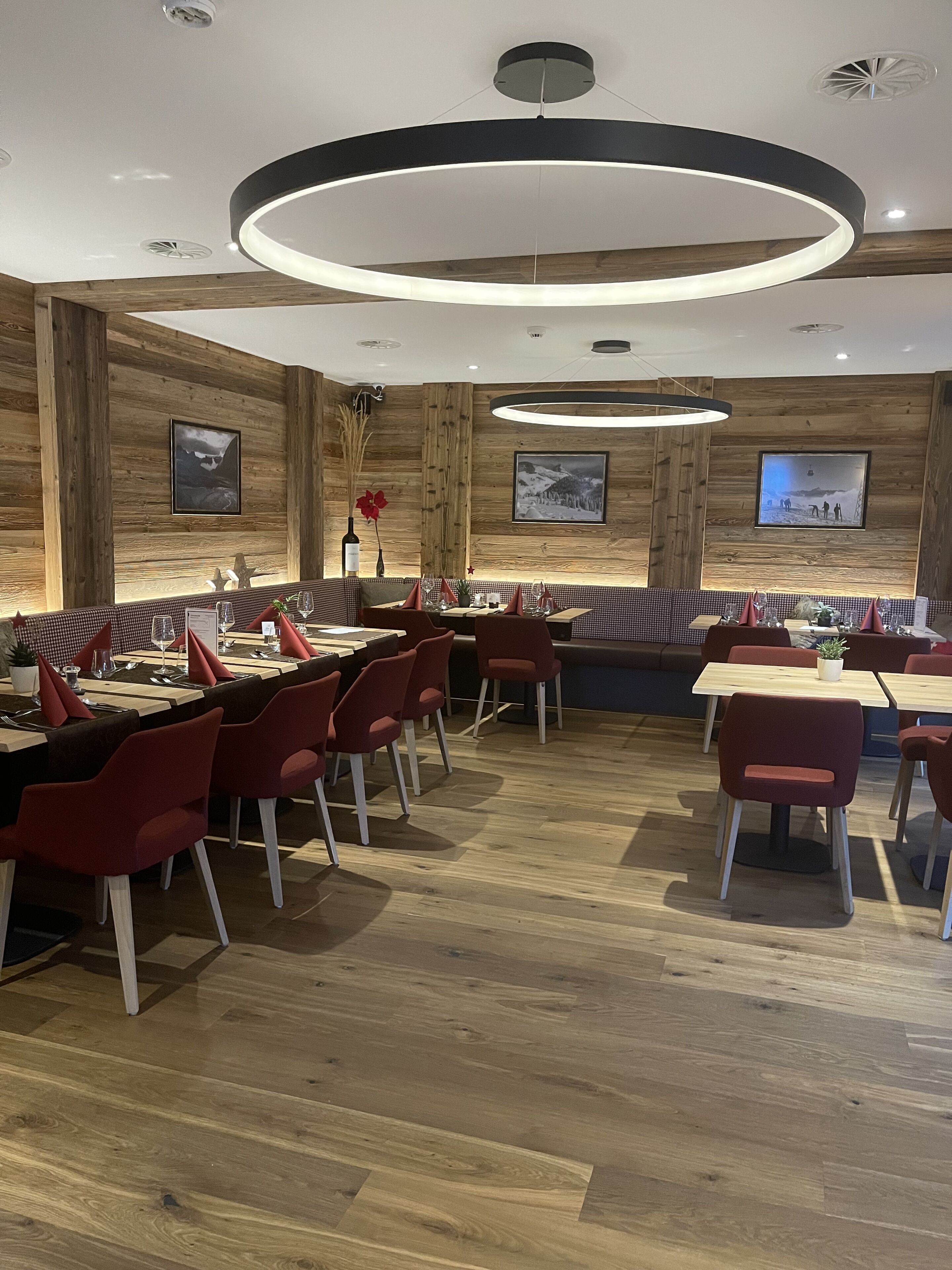 Un restaurante con paredes de madera, iluminación moderna y sillas rojas.
