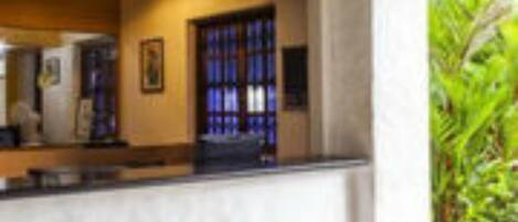 A reception area with a marble counter, a framed picture on the wall, and a large window with blue curtains.
