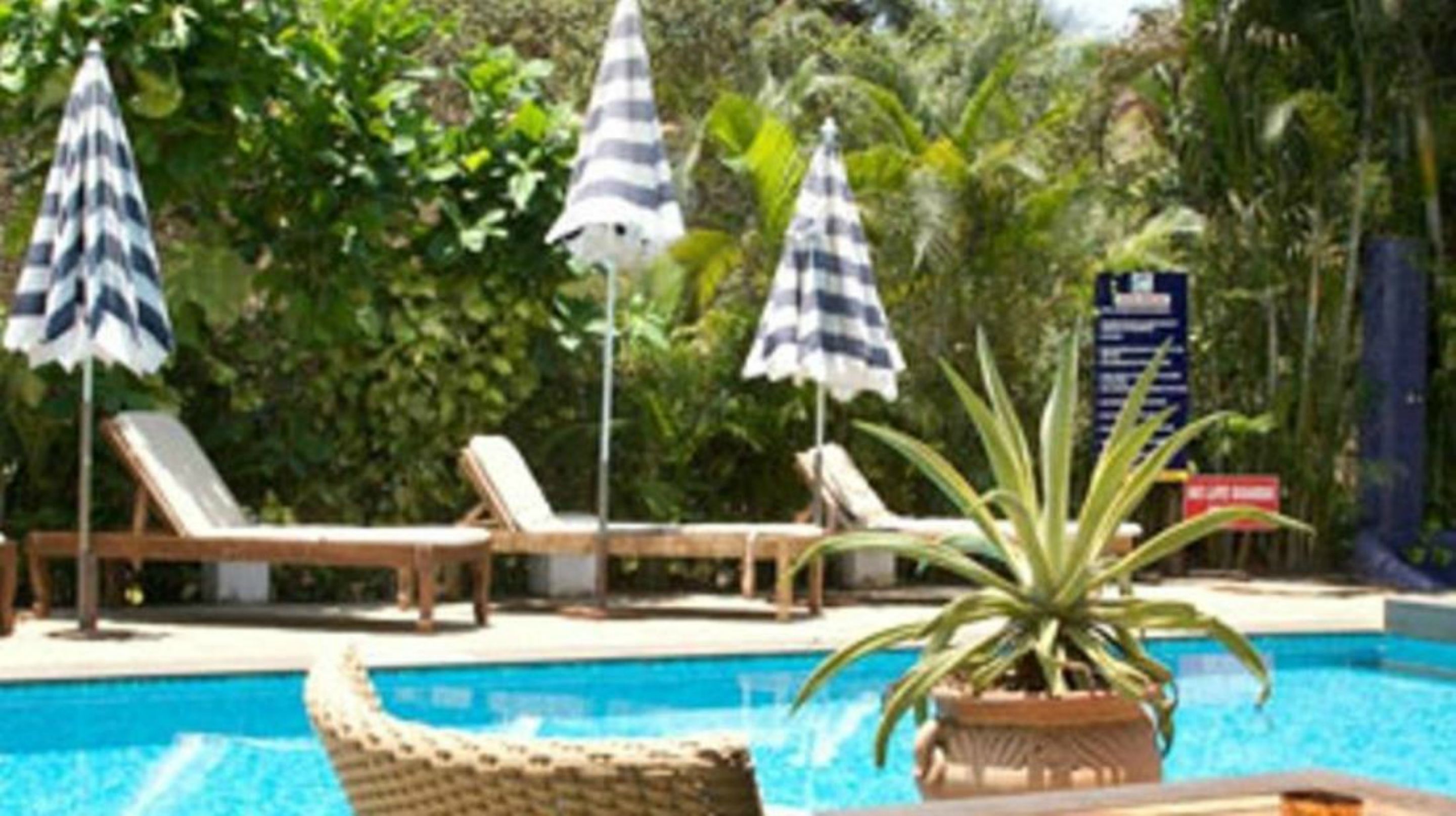 A pool area with lounge chairs and striped umbrellas.