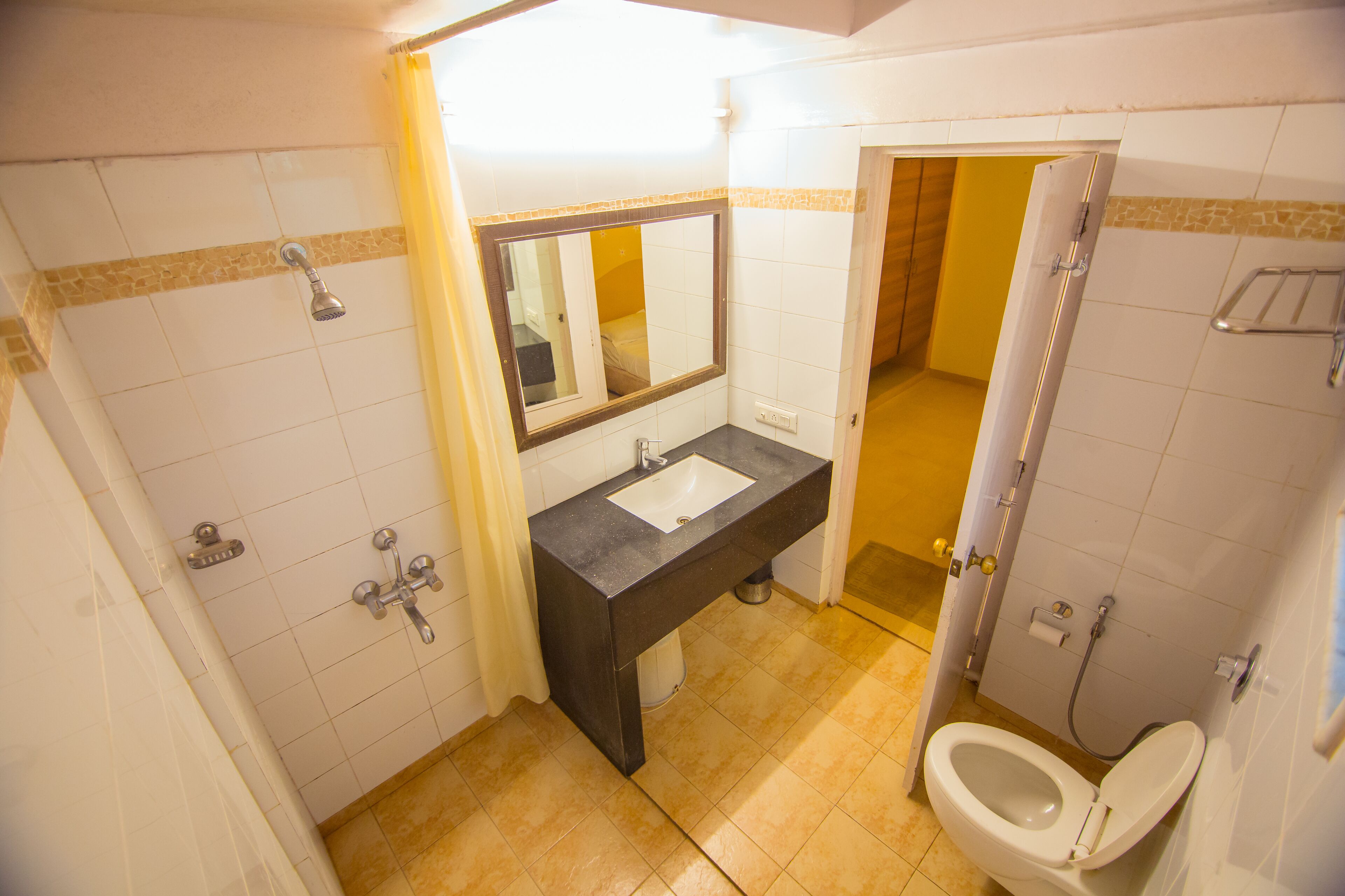Une salle de bain équipée d’un lavabo, d’un miroir, d’une douche et de toilettes.