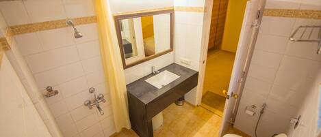 Un baño con lavamanos, espejo, ducha e inodoro.