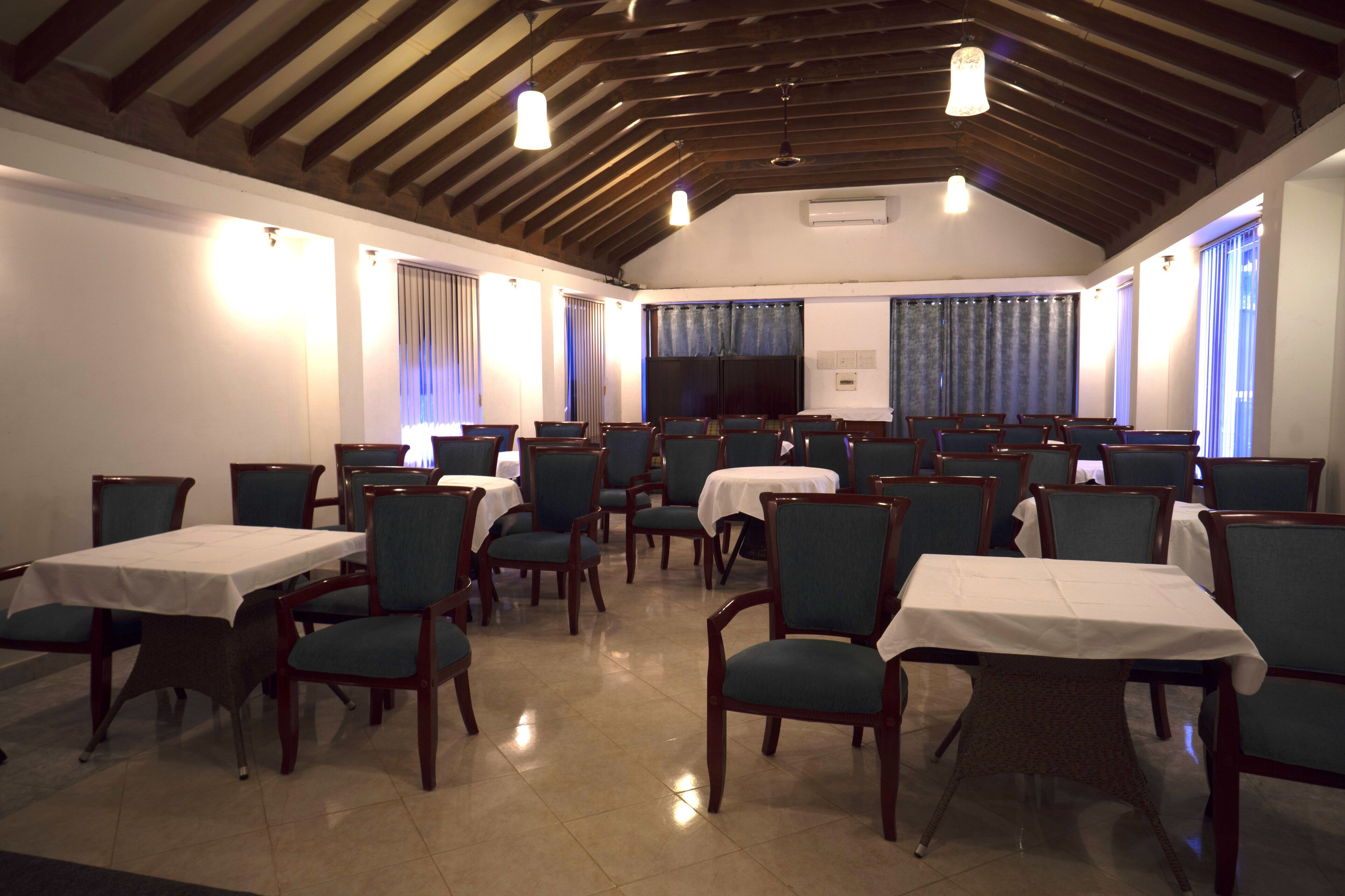 A dining area with multiple tables and chairs, a television screen, and a wooden ceiling.
