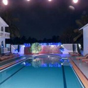 A swimming pool with a clear view of the water, surrounded by a white building and a decorative wall with lights. - Colonia Santa Maria (Baga)