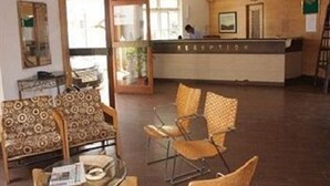 Un área de recepción con un mostrador, sillas y un muro con diseño.