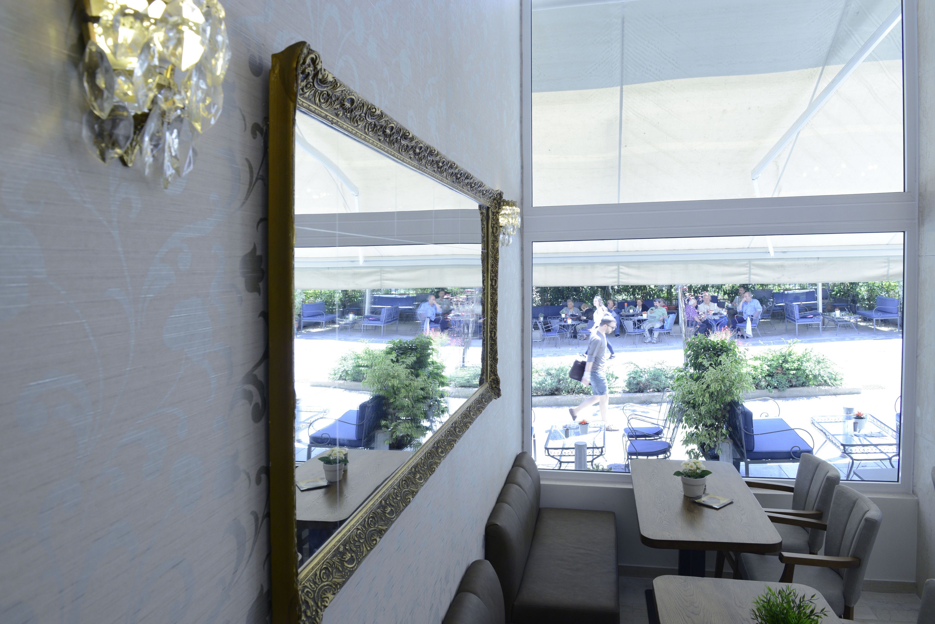 Ein Restaurant mit großem Spiegel, Sitzbereich und Blick auf die Terrassengaststätte.