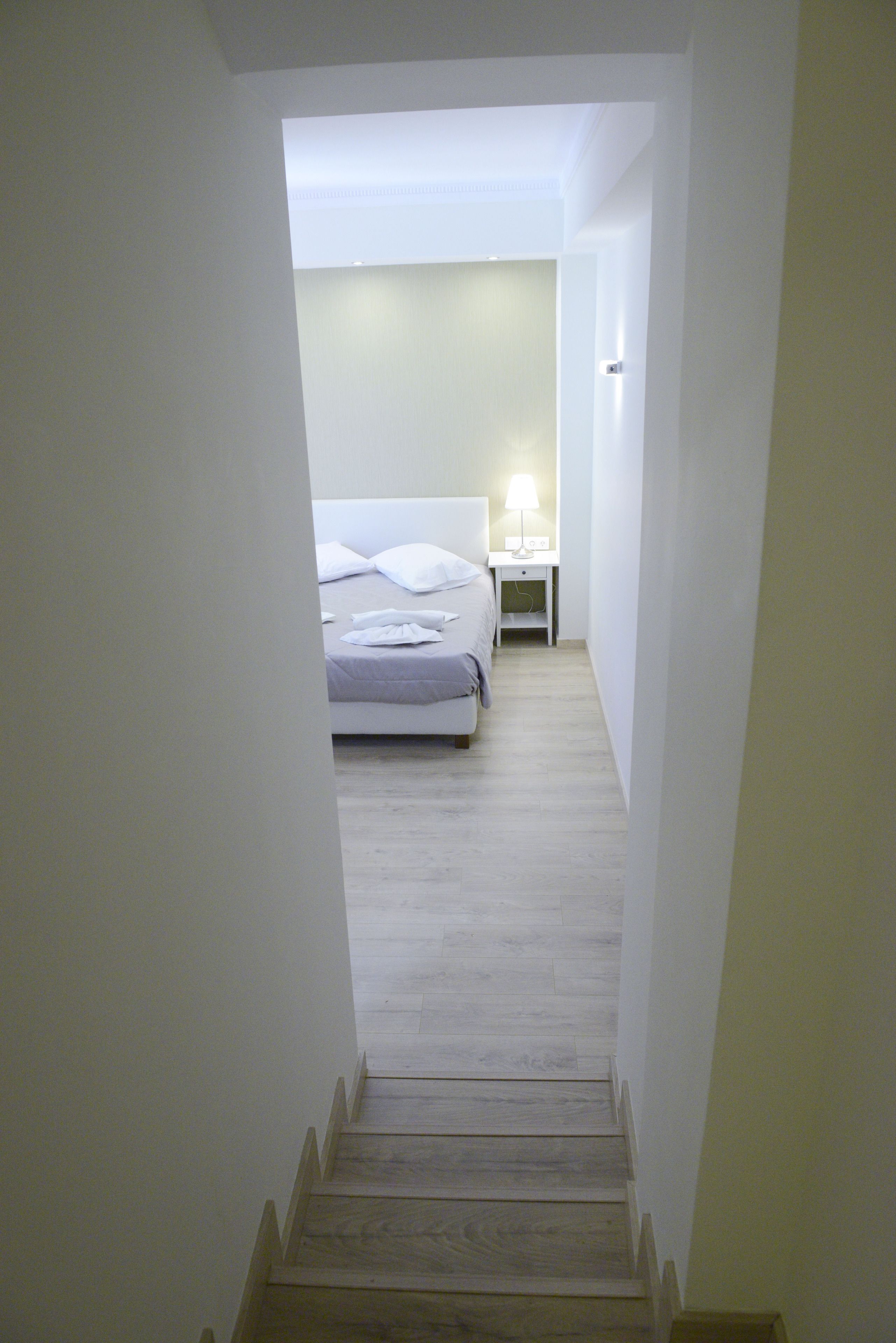 Un escalier étroit mène à une chambre à coucher qui contient un lit, une table de chevet et une lampe.