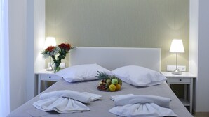 Un lit bien fait, avec du linge de lit blanc, une corbeille de fruits et un vase de fleurs sur la table de chevet.