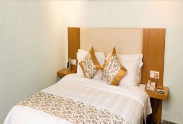 A neatly made bed with patterned bedding, a wooden headboard, and bedside tables with a phone and a small item on one of them. - Shanshui Trends Hotel LuoHu ShenZhen (Shenzhen)
