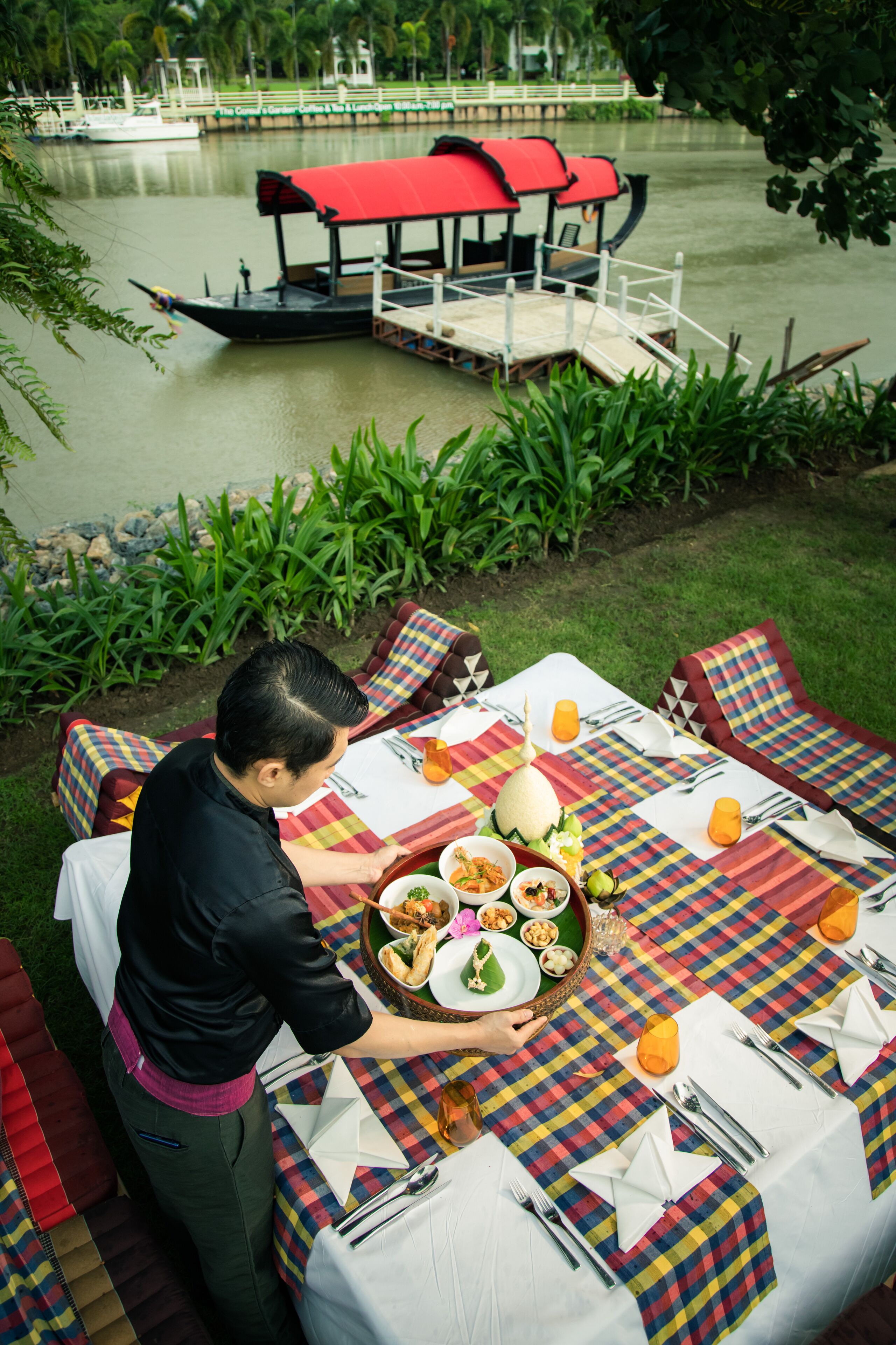 A dining table set outdoors with a view of a lake and a boat dock.