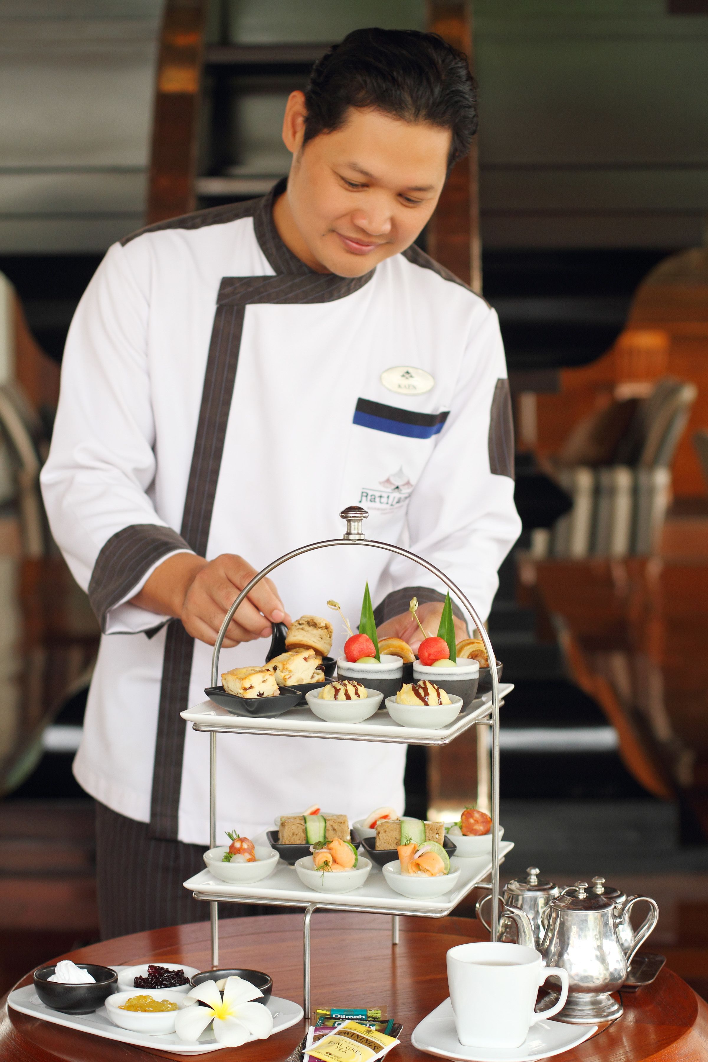 A chef arranging a tiered tray of assorted pastries and desserts.