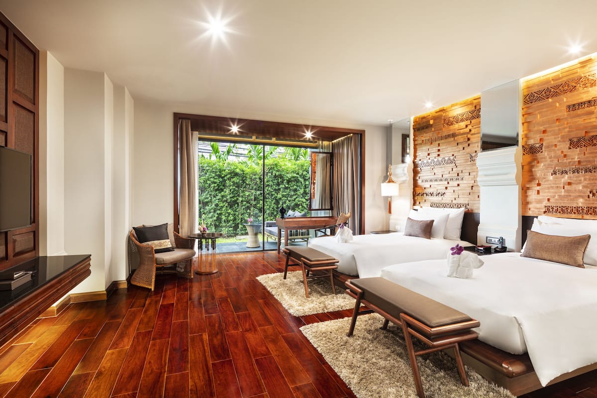Quarto de hotel com cama grande, escrivaninha, cadeira e televisão.