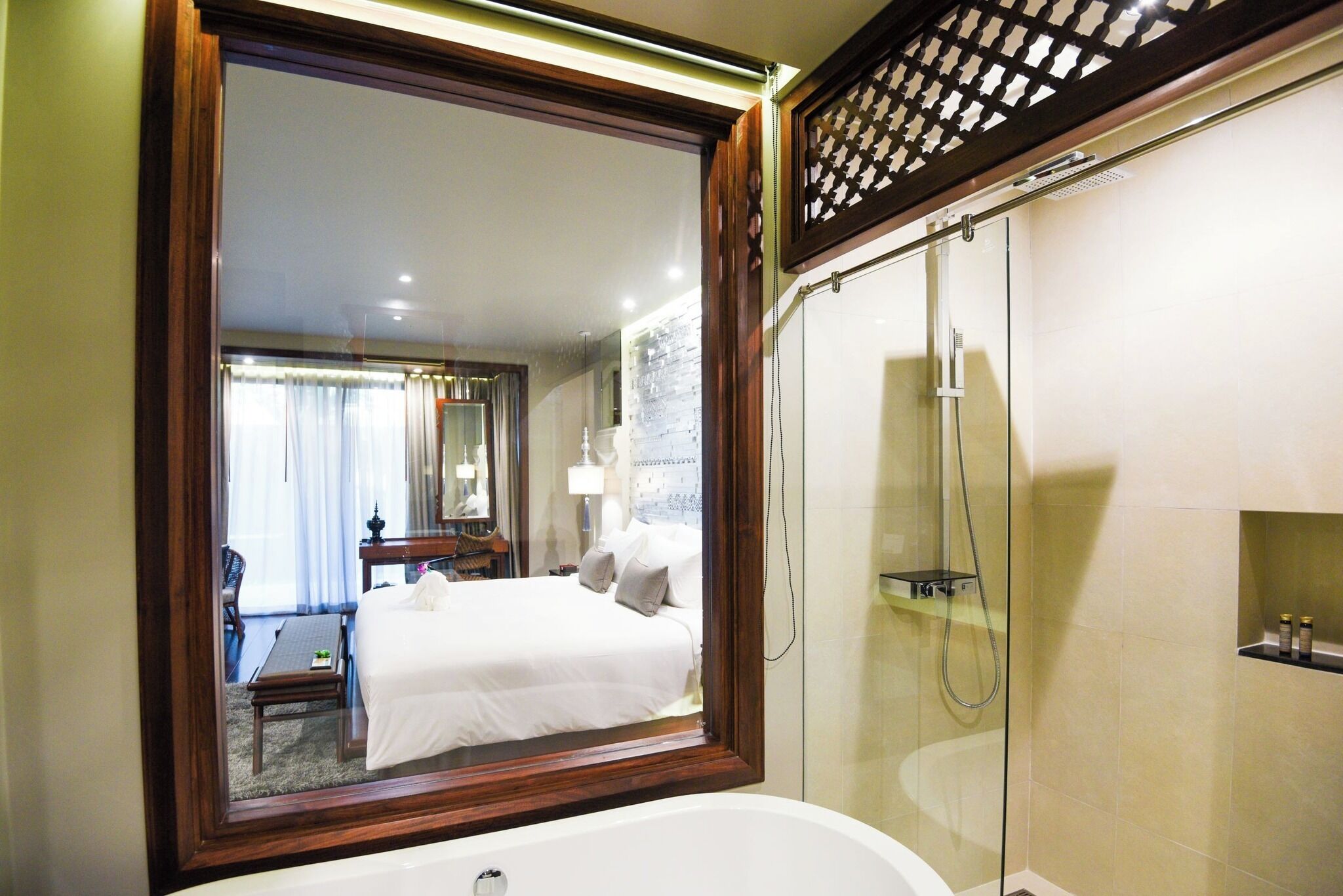 A hotel bathroom with a large mirror, a bathtub, and a glass-enclosed shower.