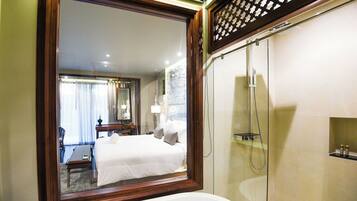A hotel bathroom with a large mirror, a bathtub, and a glass-enclosed shower.