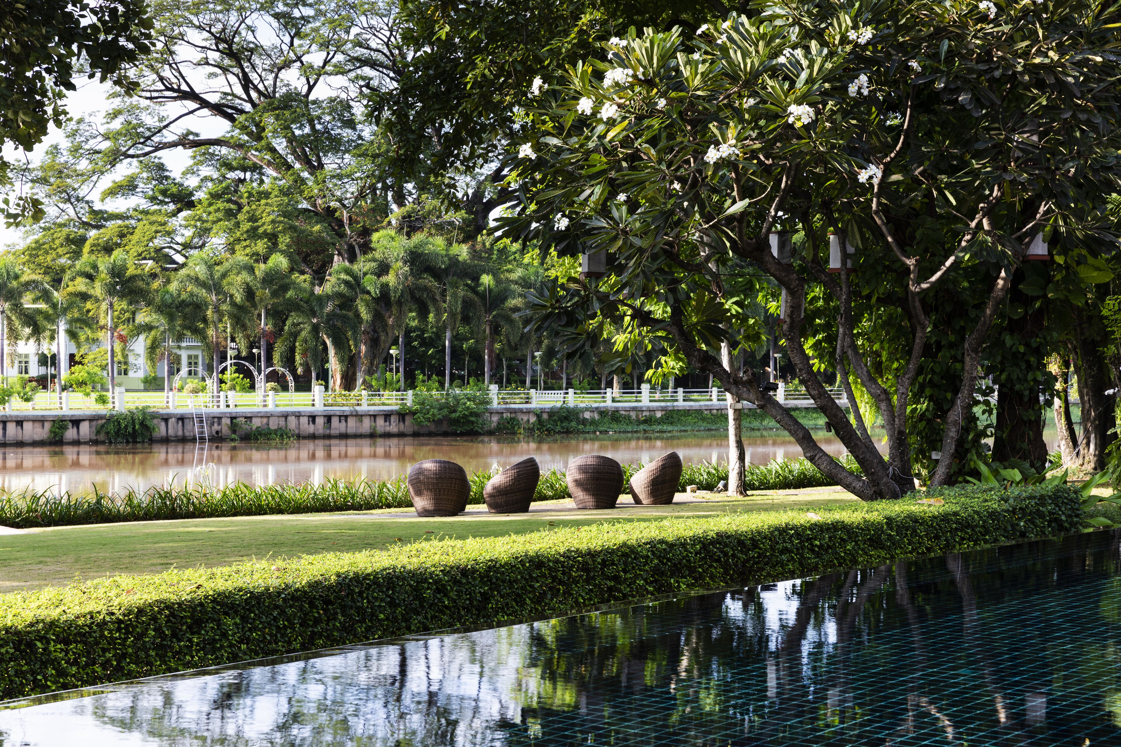 A landscaped area with a reflective pool, neatly trimmed hedges, and large decorative planters.
