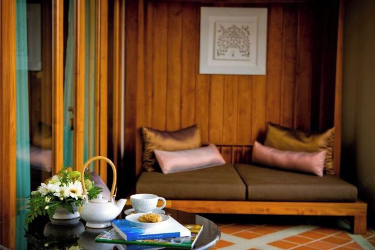 Une pièce chaleureuse avec un mur en bois, un canapé avec des coussins, une petite table sur laquelle se trouvent une théière, une tasse et un livre.