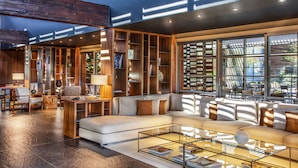 A modern living room with a large sectional sofa, glass coffee table, and wooden bookshelves. - Jiva Hill Resort - Genève (Crozet)