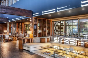 Uma sala de estar moderna com um amplo sofá seccional, mesa de centro de vidro e estantes de madeira.