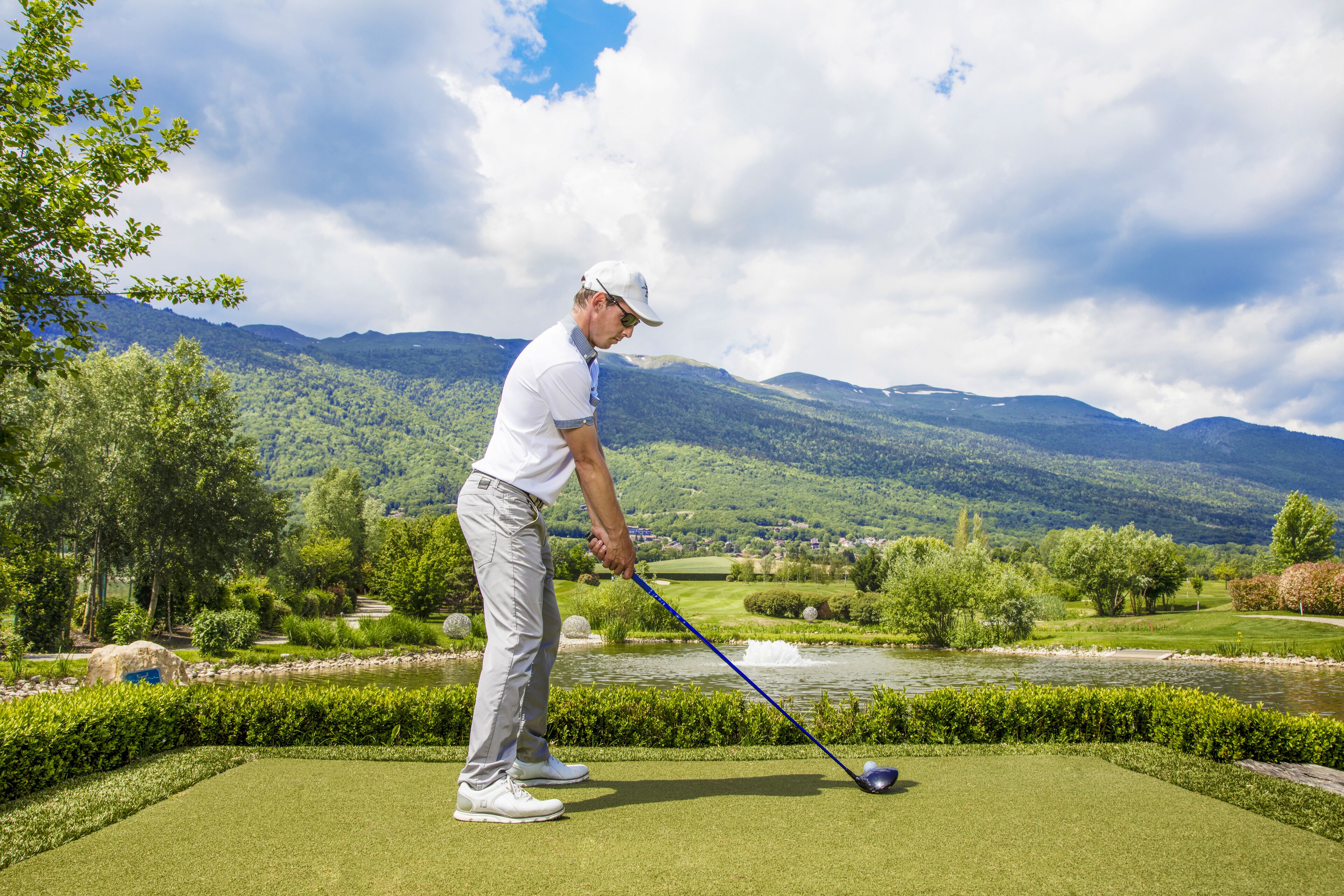 Un golfista en un campo verde con montañas pintorescas al fondo.