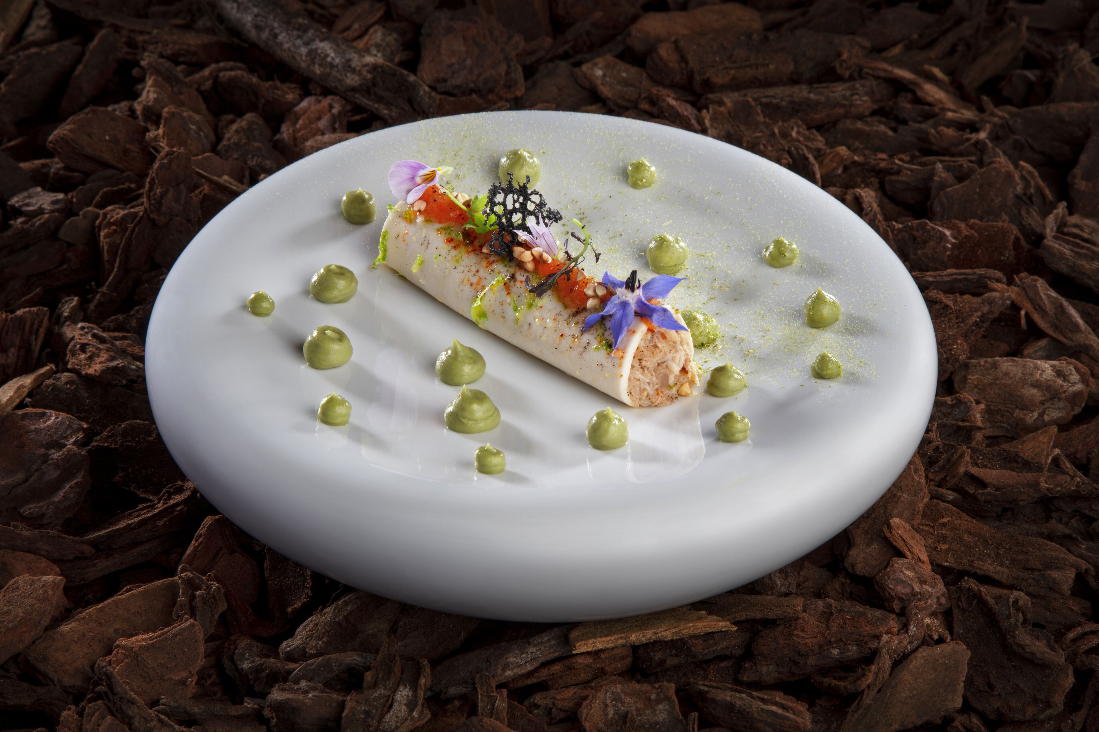 A dessert on a white plate with green dots and a chocolate background.
